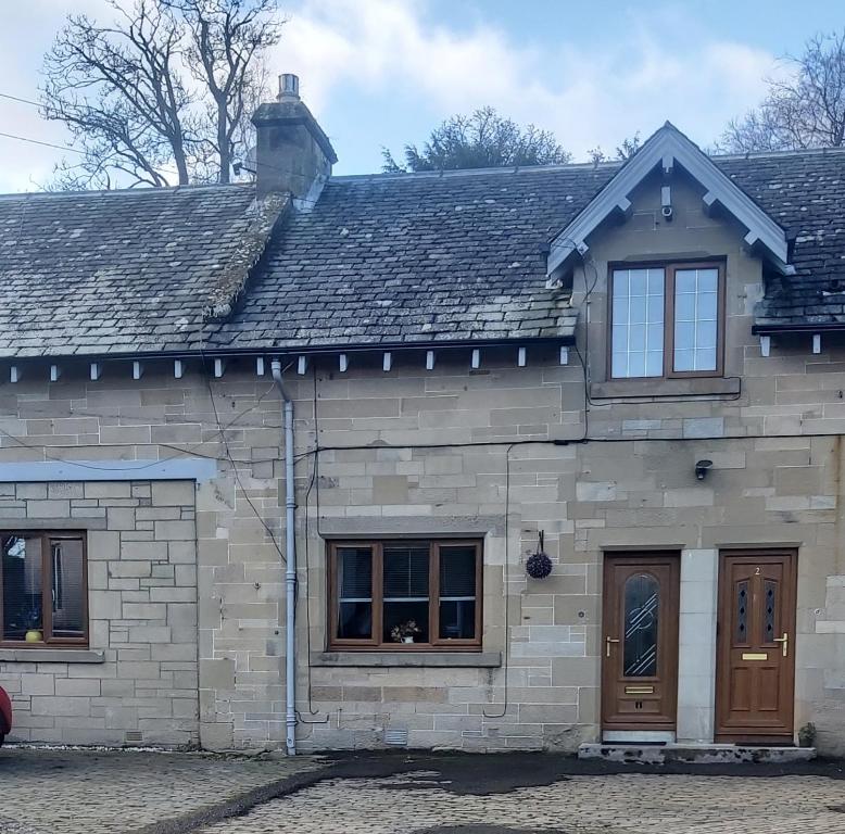 TorwoodleeBalnakiel Cottage, Galashiels的一座石头房子,设有两扇窗户和屋顶