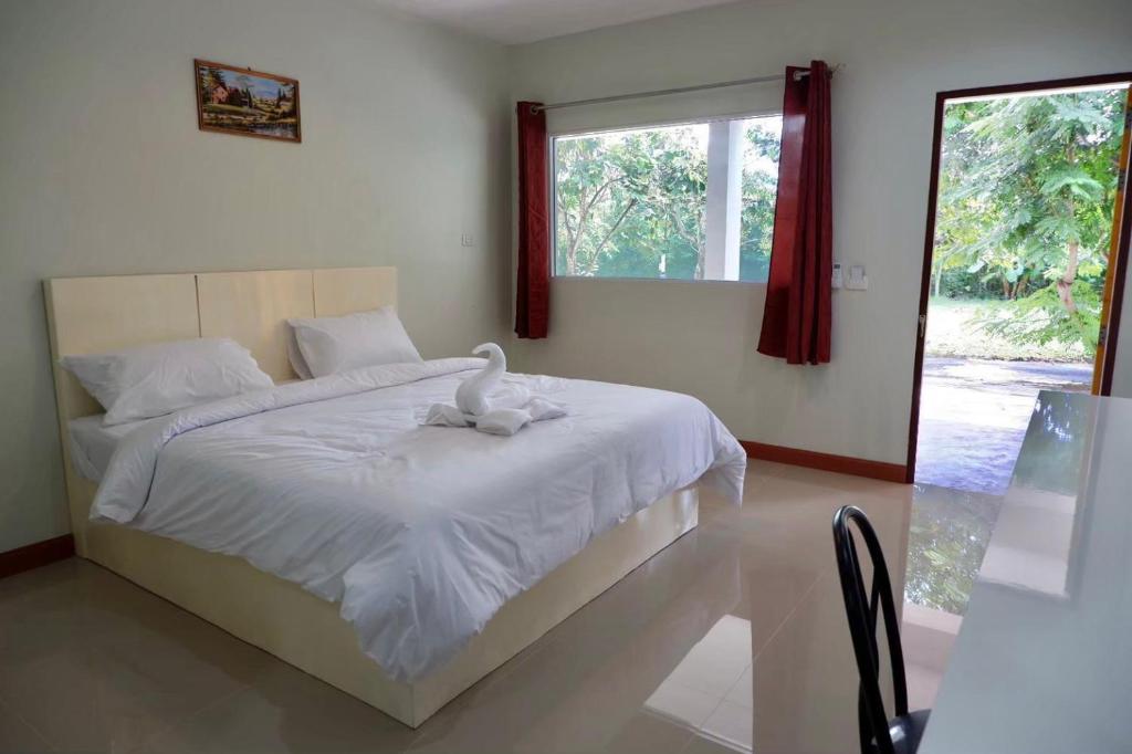 苏安庞โรงแรมคอมม่อนเวลธ์ Commonwealth Hotel&Resort的卧室配有白色的床和天鹅