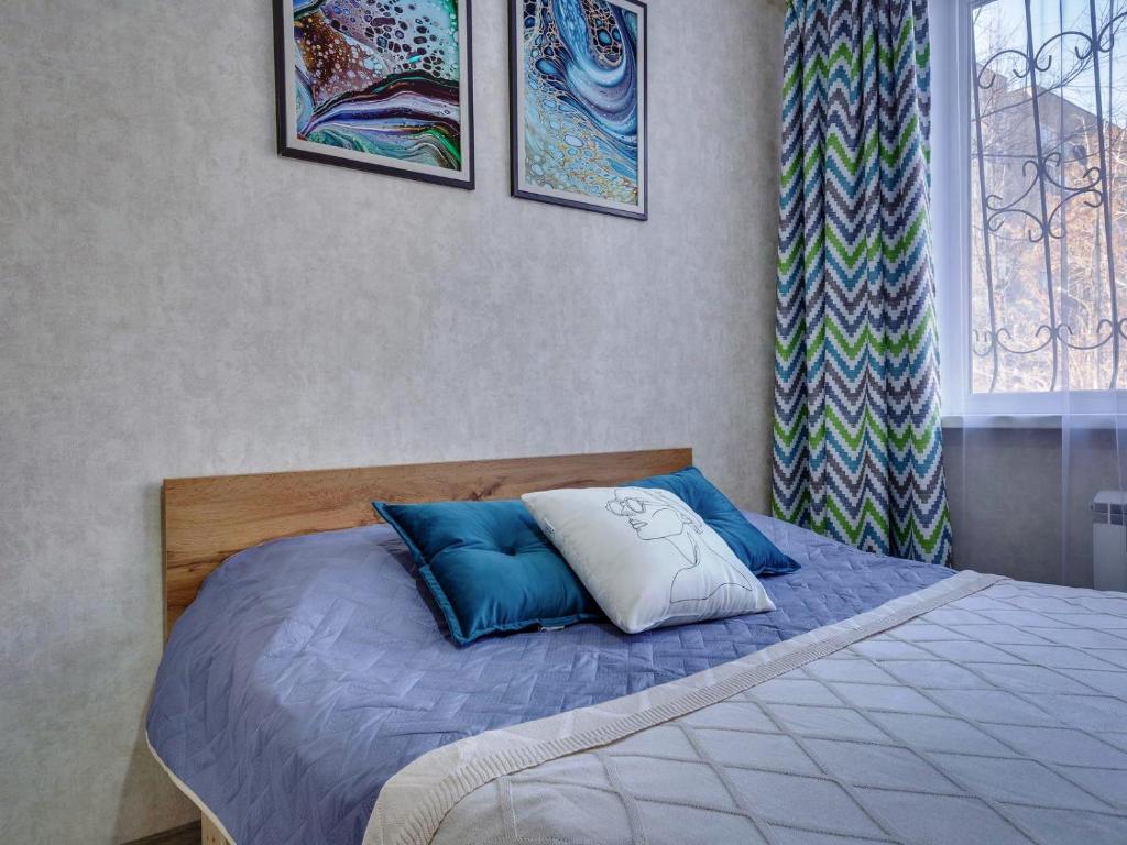 阿拉木图YourHouse на Толе би Весновка的卧室内的一张带蓝色和白色枕头的床