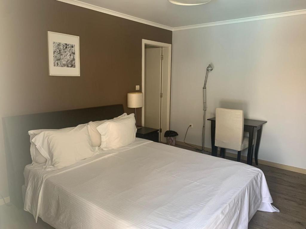 罗安达Casas de Luanda GH-Miramar的卧室配有一张白色的床、一张桌子和一把椅子