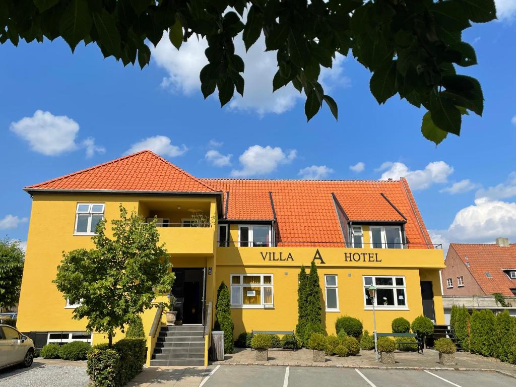欧登塞Villa A Hotel的黄色建筑,有红色屋顶