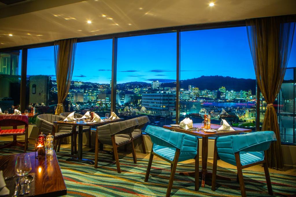 惠灵顿东方海湾惠灵顿国敦酒店的餐厅设有桌椅和大窗户。