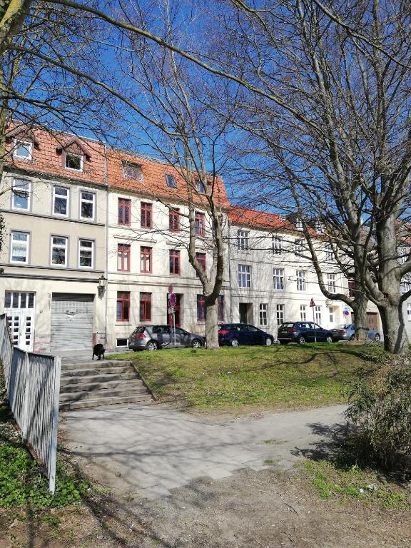 维斯马Turmstrasse19的一座白色的大建筑,前面有汽车停放