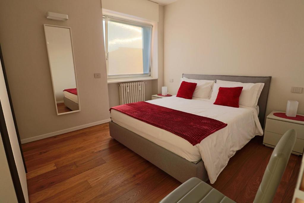米兰伊索拉公寓式酒店的一间卧室配有一张带红色枕头和镜子的床