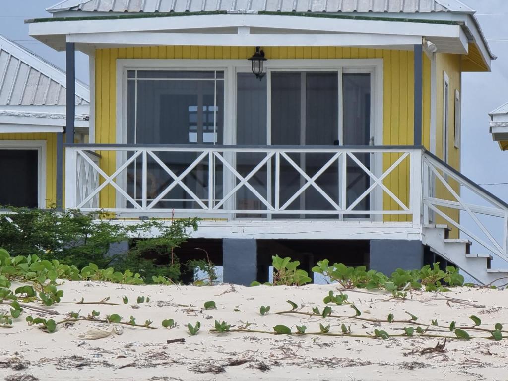Codrington VillageComfortable 1-Bed Cottage in Codrington Barbuda的海滩上带门廊的黄色房子