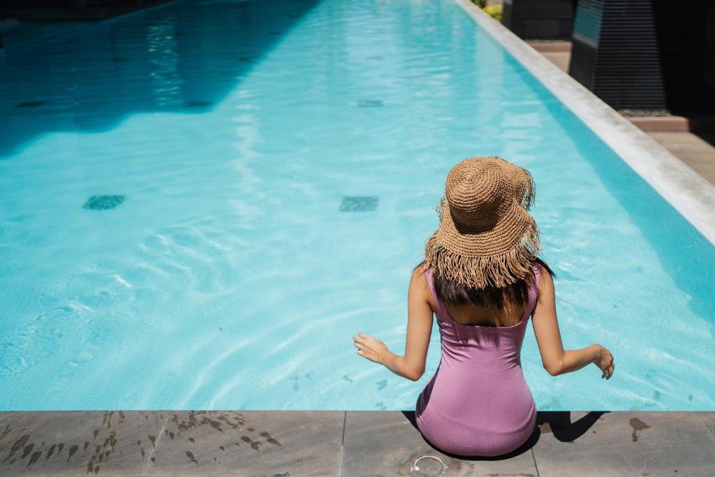 斯利马外交官酒店的坐在游泳池旁的戴帽子的女人