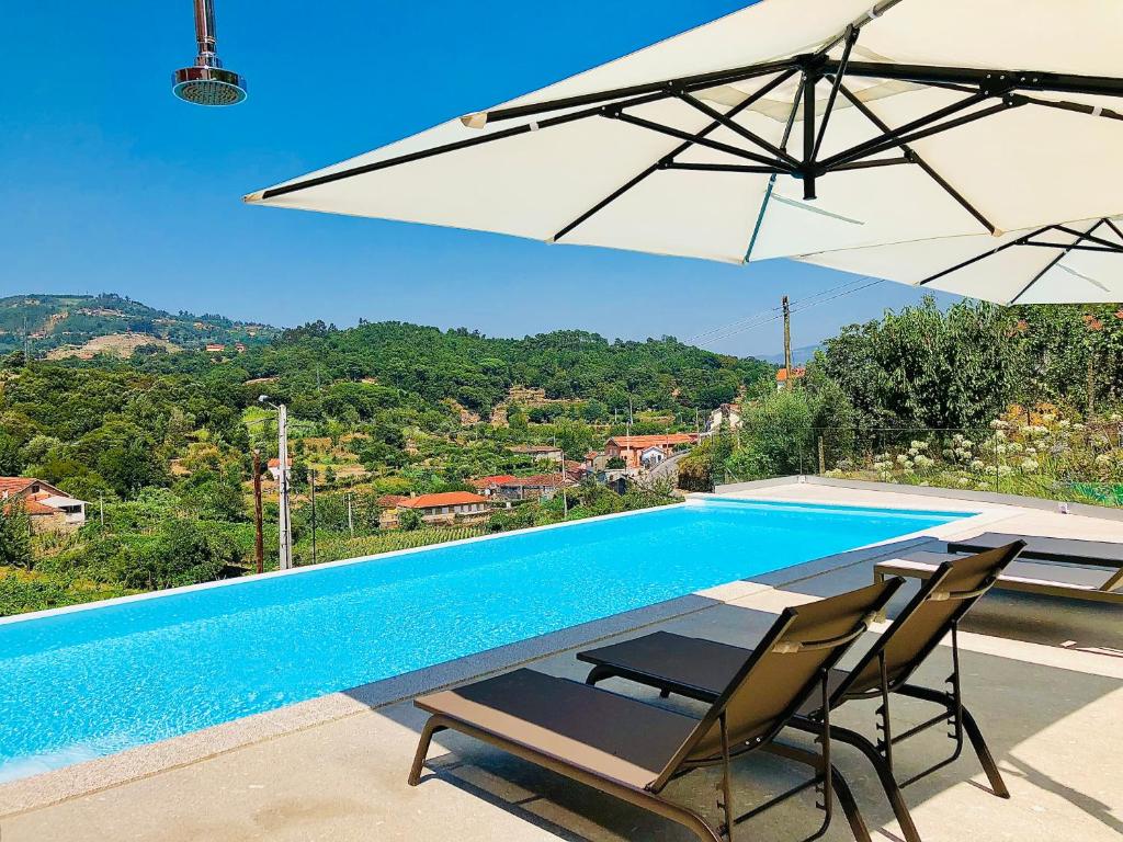 Santa Cruz do DouroSolar Do Douro的一个带两把椅子和遮阳伞的游泳池