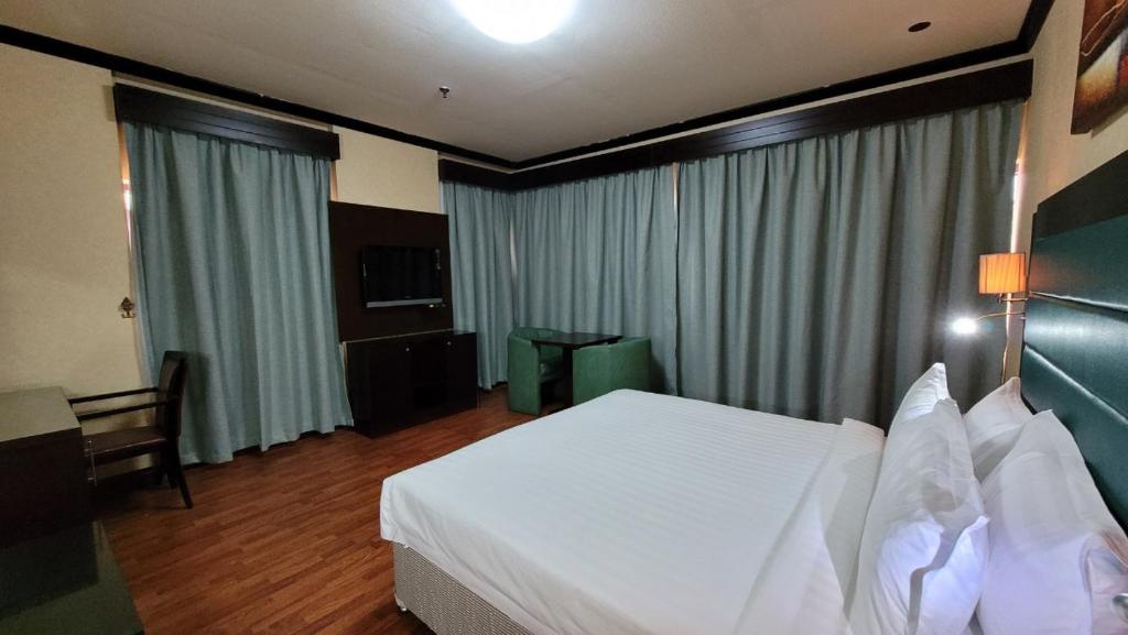 阿布扎比斯特朗德酒店的酒店客房设有白色的床和电视。