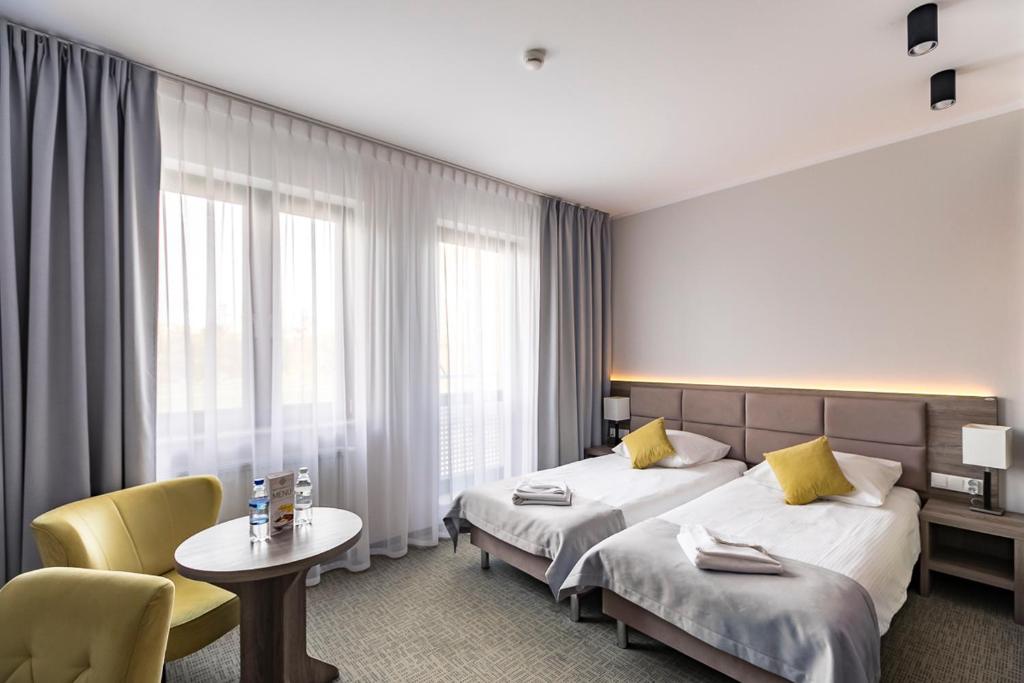 波兹南Meet Poznań Hotel的酒店客房设有两张床和一张桌子。