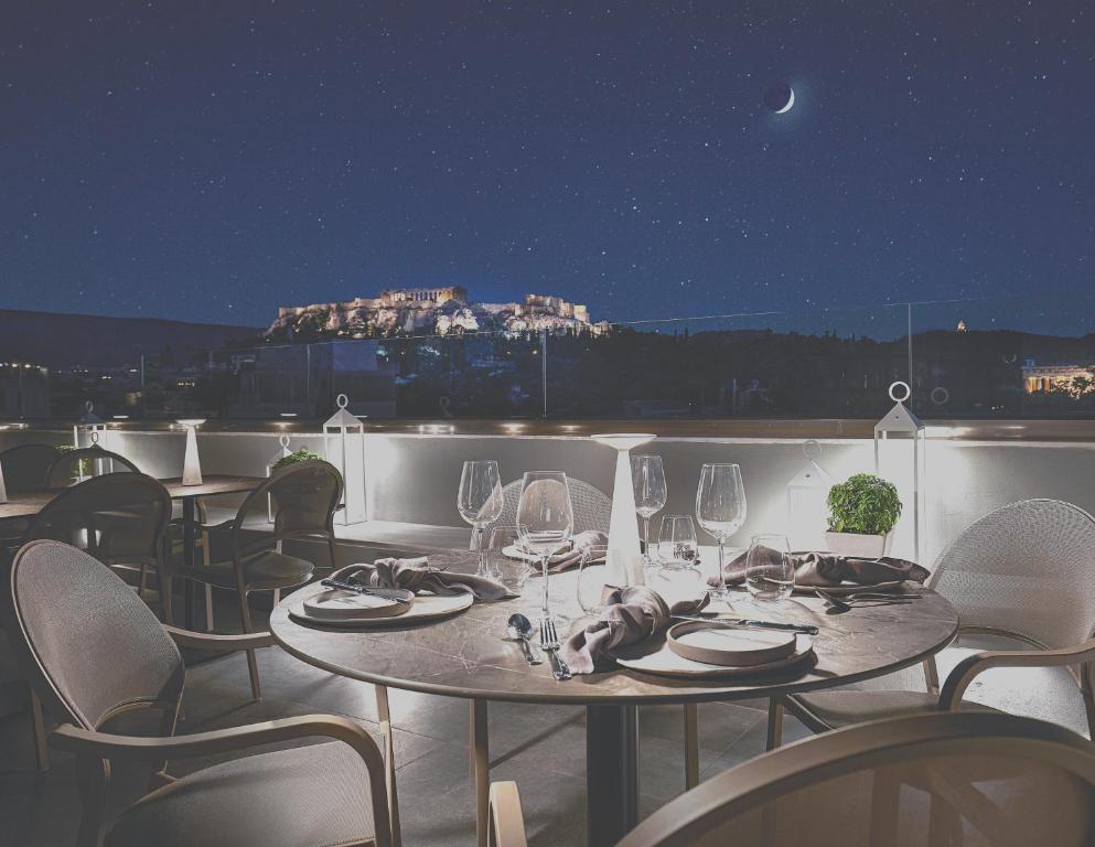 雅典MiraMe Athens Boutique Hotel-House of Gastronomy的晚间在阳台上摆放着酒杯的桌子