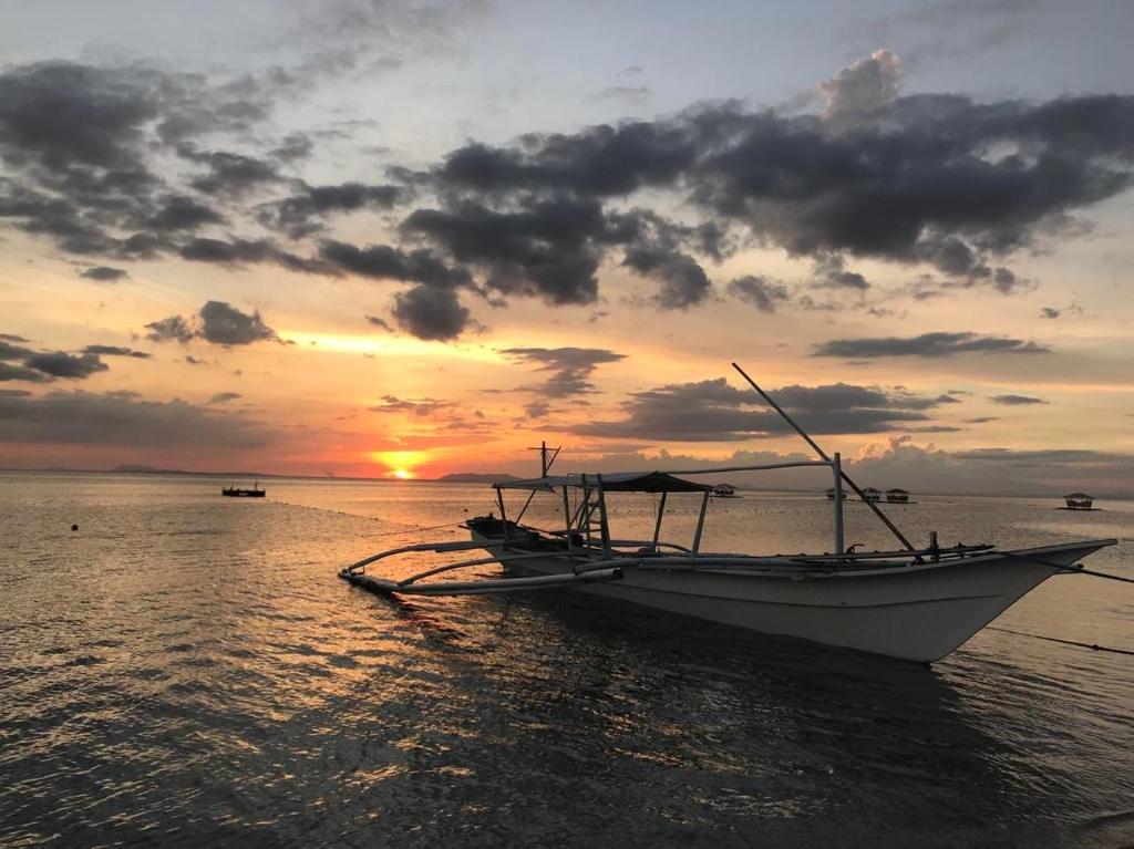 马比尼Manzil Anilao B&B的水中的小船,背景是日落