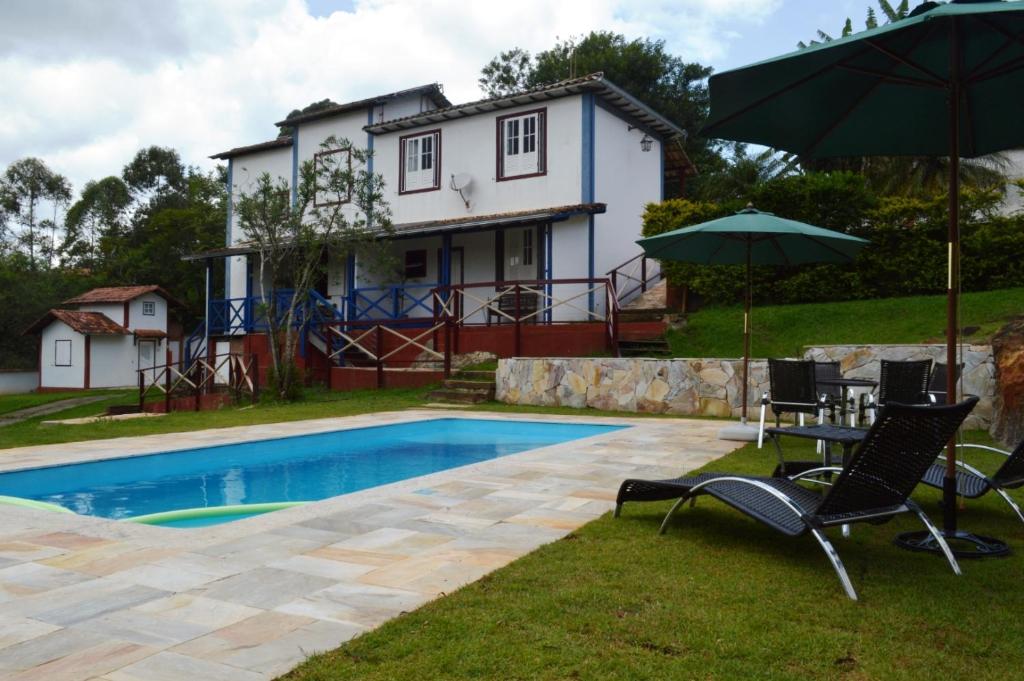 拉夫拉斯诺瓦斯Pousada Villa Verde的一个带椅子和遮阳伞的游泳池以及一间房屋