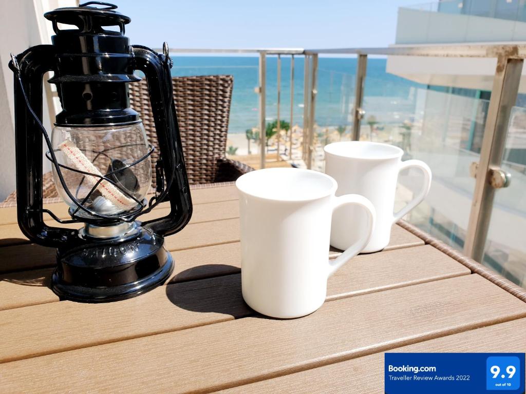 北马马亚-讷沃达里Seaview studio private parking included - Beach Residence的阳台上的2个白咖啡杯和搅拌机