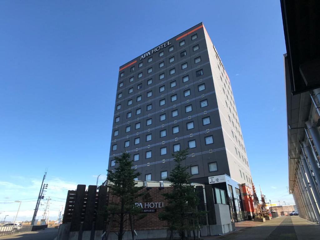 上越市APA Hotel Joetsu Myoko-Ekimae的一座高大的建筑,旁边有一个标志