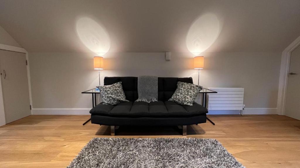 邓布兰NEW 1BD Contemporary Flat Upper Dunblane的客厅里一张黑色沙发,配有两盏灯