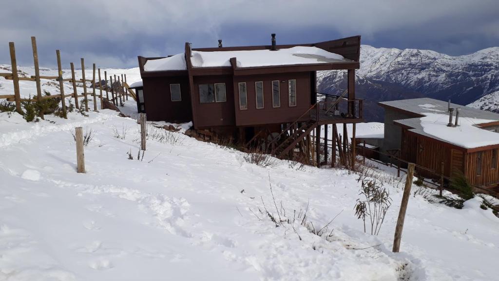 圣地亚哥Casa en Farellones的雪中小屋,带栅栏和山脉