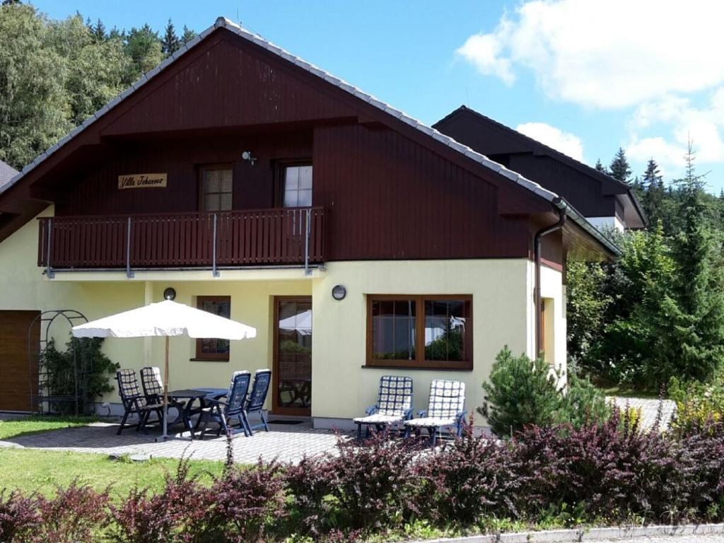 Kramolínbeautiful villa at the Lipno Lake with ski pistes的房屋前有椅子和遮阳伞