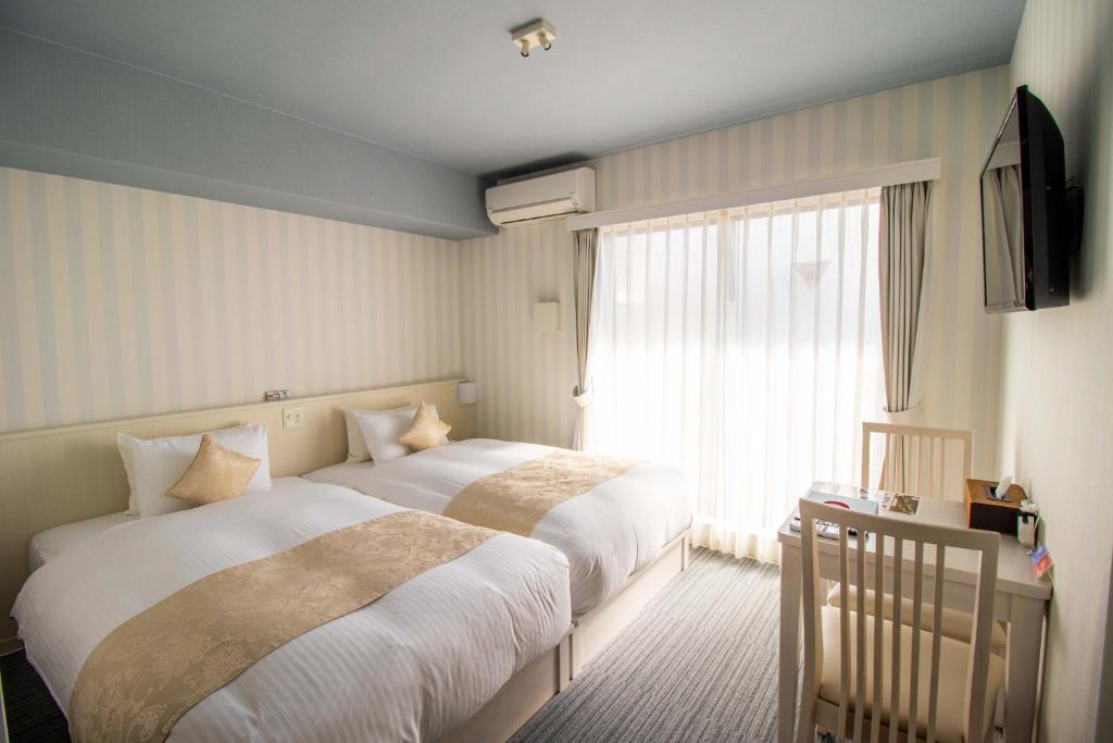 京都Framboise KYOTO Hotel de charme的酒店客房设有两张床和窗户。