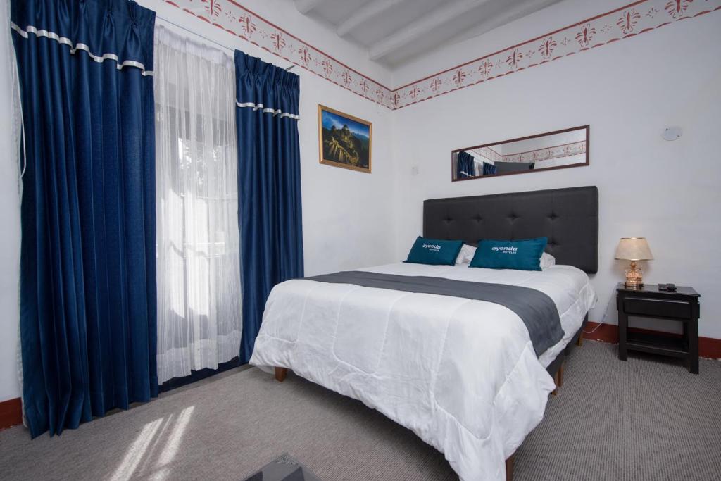 库斯科Ayenda Miski Tayta的一间卧室配有一张带蓝色窗帘的大床