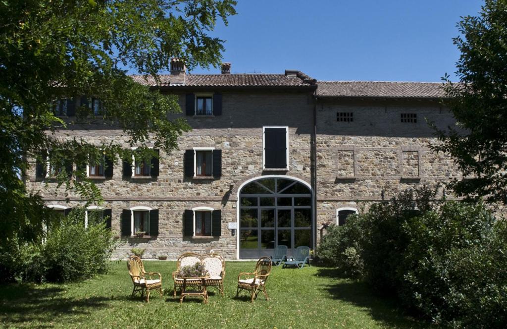 斯坎迪亚诺Agriturismo Il Brugnolo的一座老石头建筑,在院子里摆放着椅子