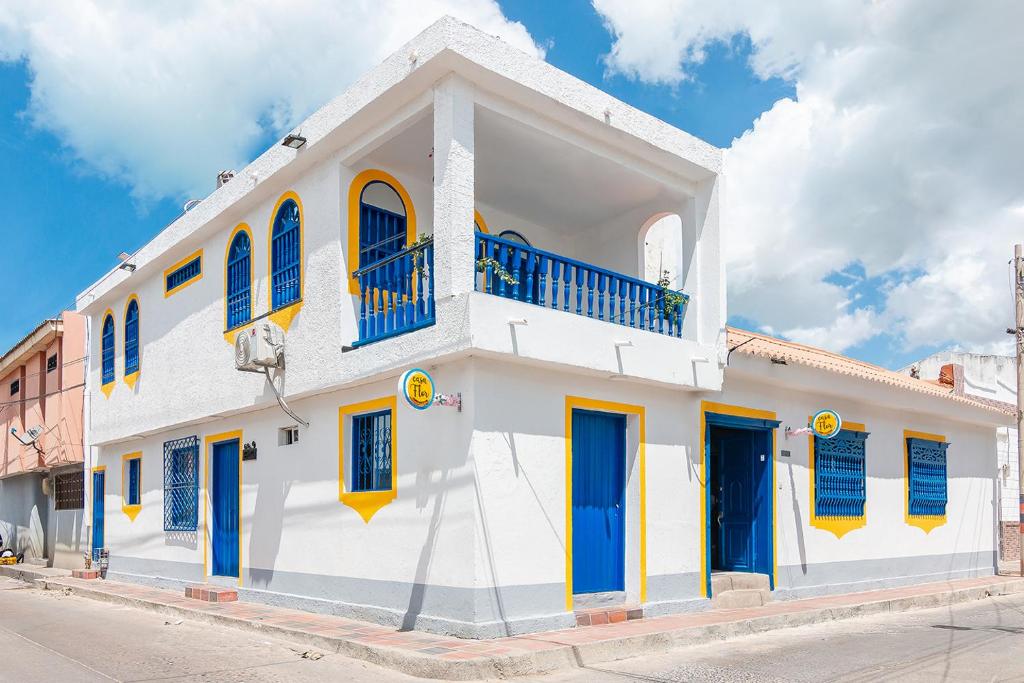 里奥阿查Casa Flor Hostel & Drinks的白色的建筑,设有蓝色的窗户和蓝色的百叶窗