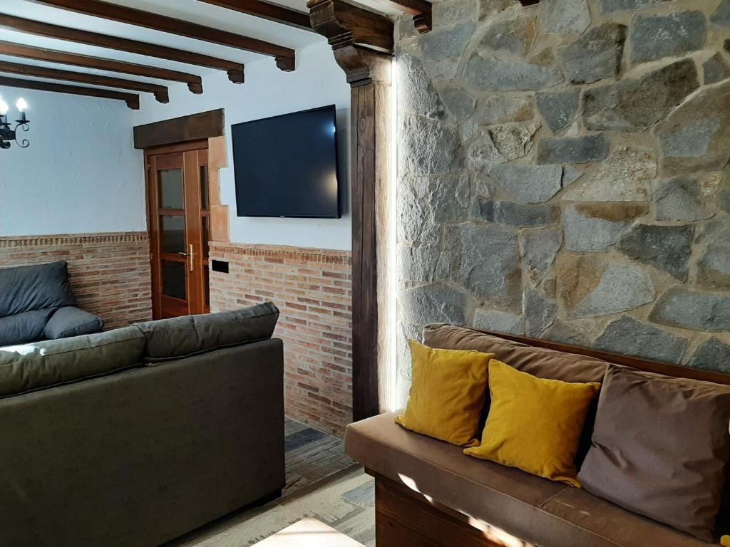 SotoserranoCasa Rural El Arroyo的带沙发和石墙的客厅
