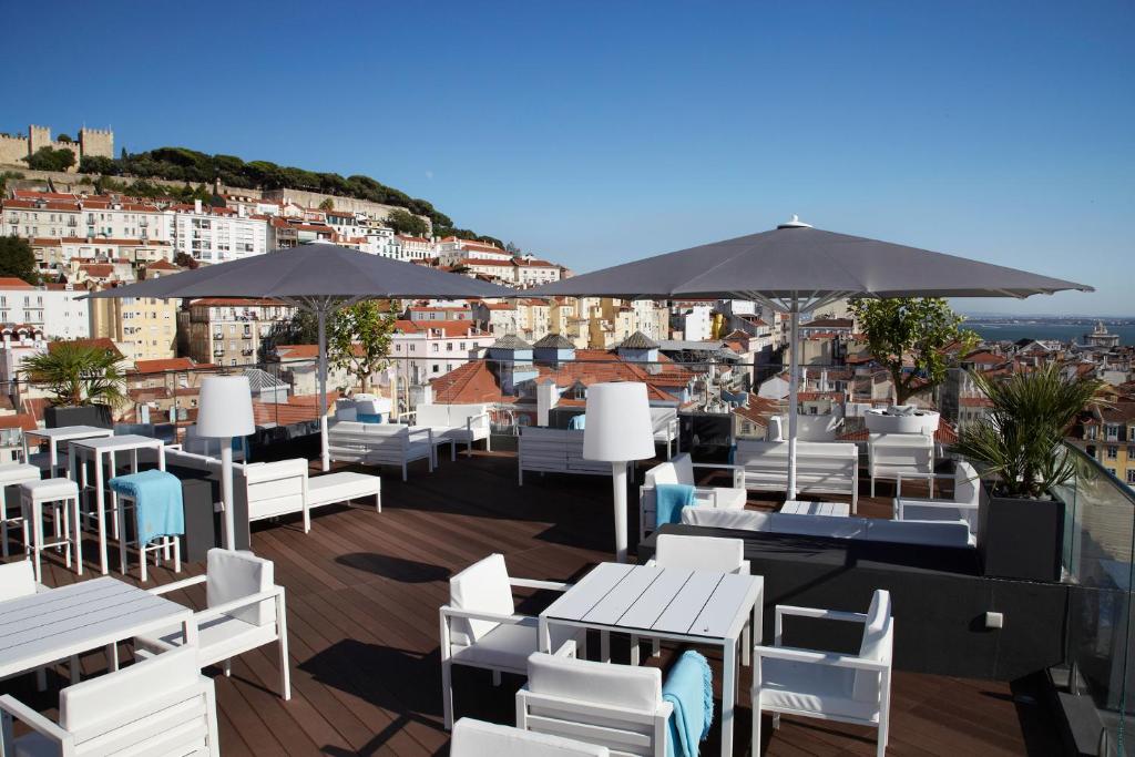 里斯本世界酒店的一间设有白色椅子、桌子和遮阳伞的餐厅