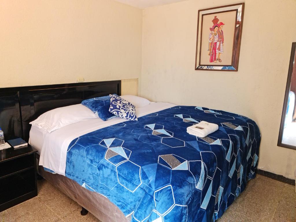 克萨尔特南戈Hotel Kasa Kamelot Las Rosas的一间卧室配有一张带蓝色和白色棉被的床