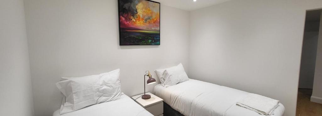 伦敦Garland Stylish Apartment 1 in Greater London的一间卧室设有两张床,墙上挂着一幅画