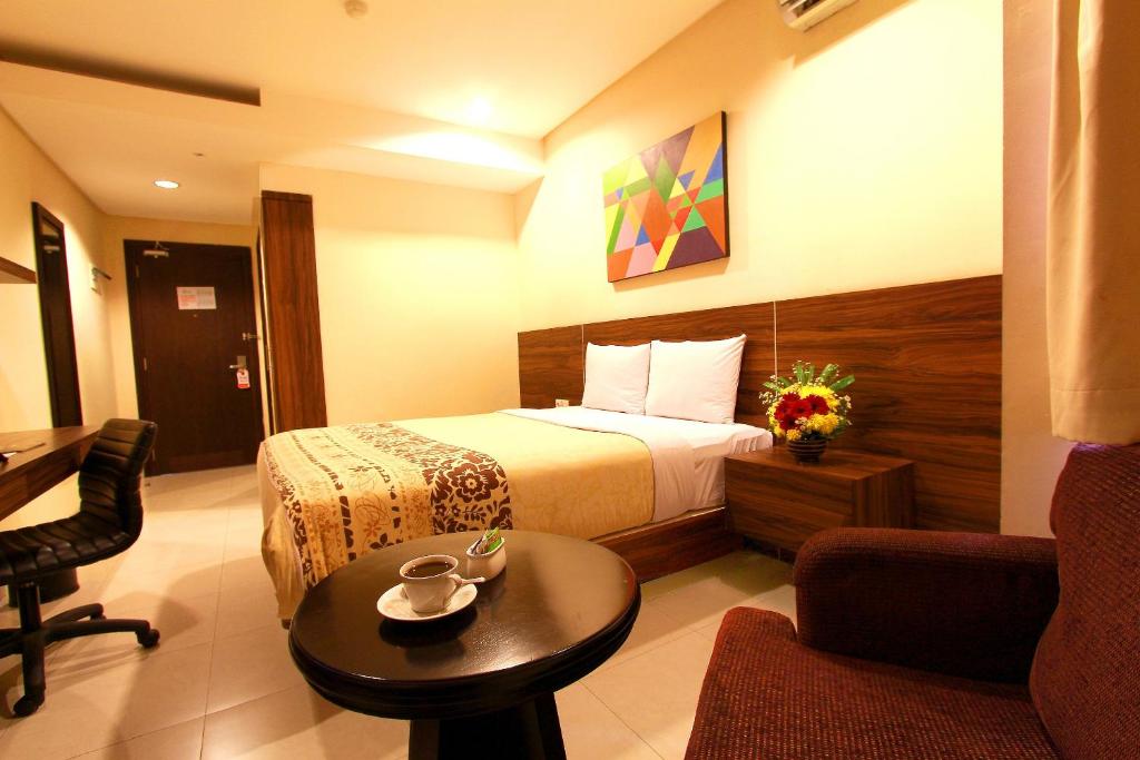 雅加达Prasada Mansion Sudirman的配有床、椅子和桌子的酒店客房