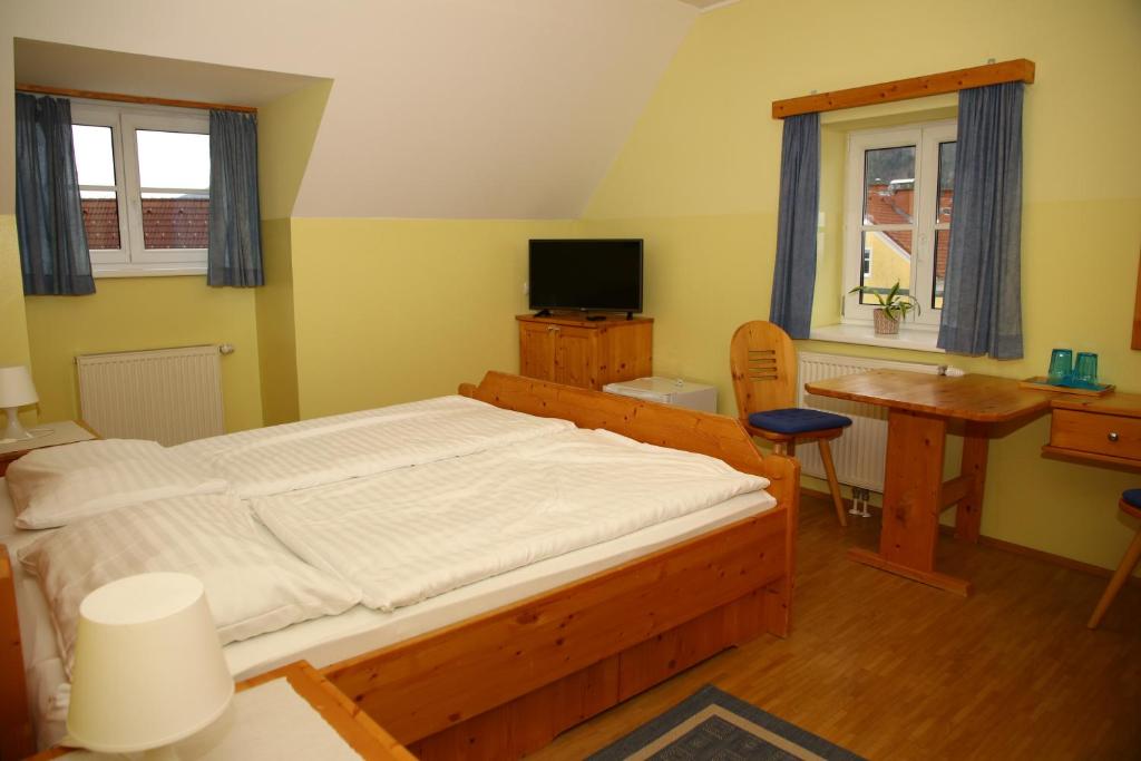 Pernegg an der MurPernegger Dorfstub´n的一间卧室配有一张床、一张书桌和一台电视