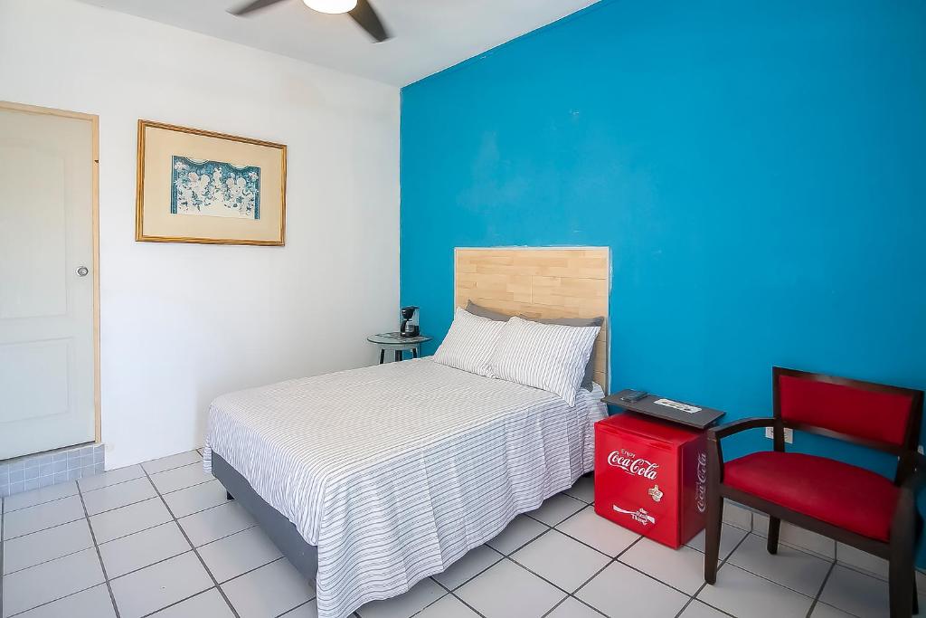 卡波圣卢卡斯OYO Hotel Plaza Las Torres, Cabo San Lucas的一间卧室配有一张床和一张红色椅子
