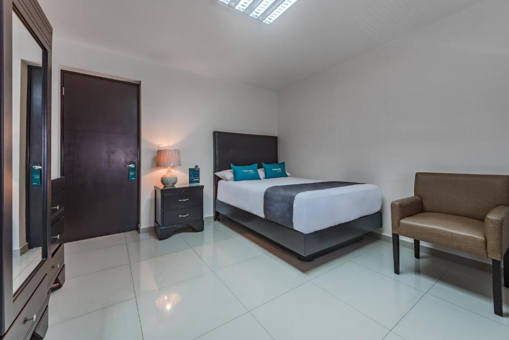 蒙特雷Ayenda Suites Ejecutivas Monterrey的一间卧室配有一张床、一把椅子和电视