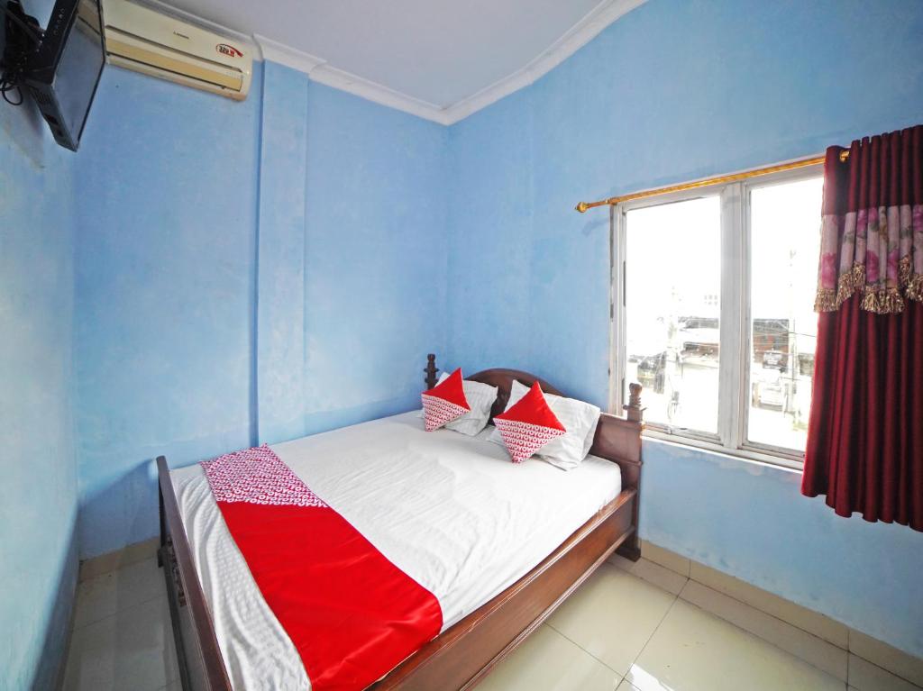 棉兰OYO 90922 Gurusinga Guesthouse的一间卧室配有一张蓝色墙壁的床和一扇窗户