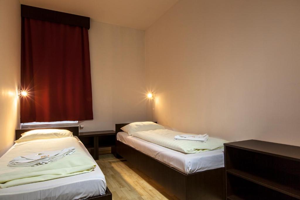 布达佩斯Prater Residence Apartment的红色窗帘间内的两张床