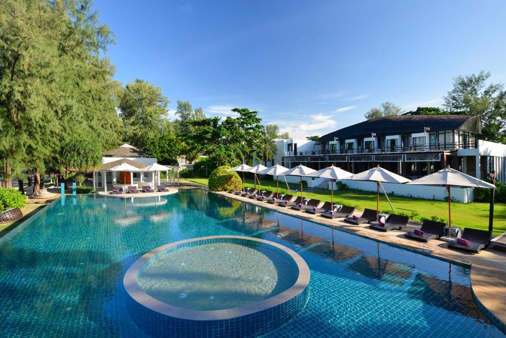 高兰Twin Lotus Resort and Spa - SHA Plus - Adult Only Hotel的一座带椅子的大型游泳池和一座建筑