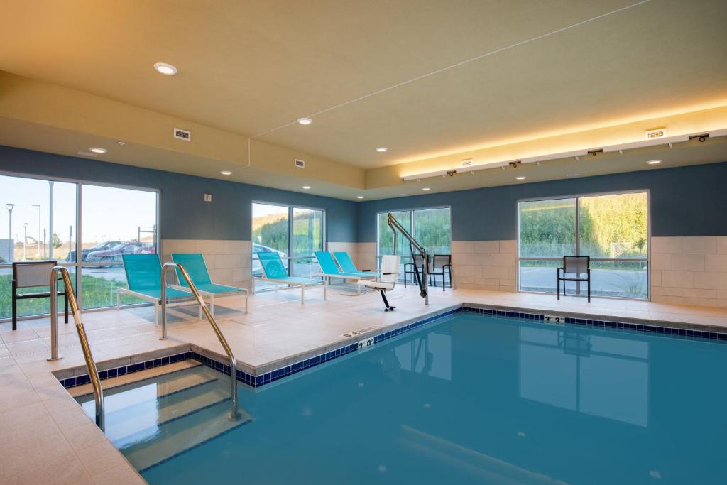 伯洛伊特Holiday Inn Express & Suites - Beloit, an IHG Hotel的一个带蓝色桌椅的大型游泳池