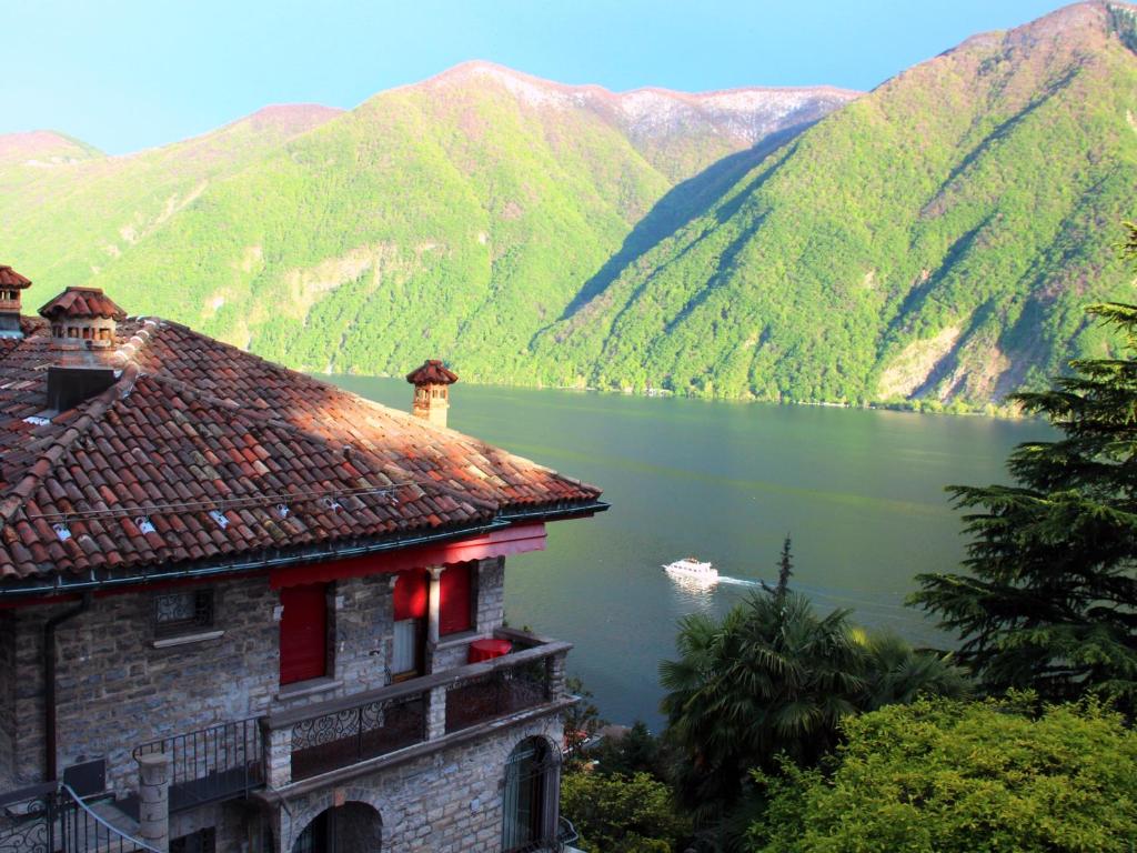 卢加诺Barony Le Pergole holiday apartments Lugano的享有湖泊和山脉景色的建筑