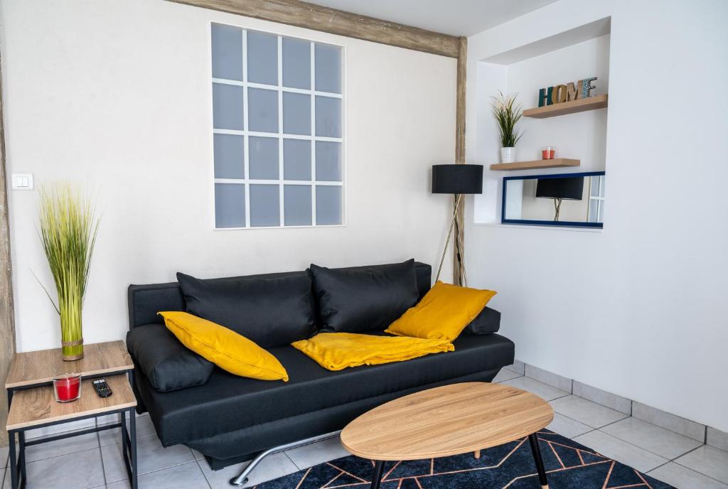 布格奈斯Le 4midable - Chaleureux 2 pièces的客厅配有黑色沙发和黄色枕头