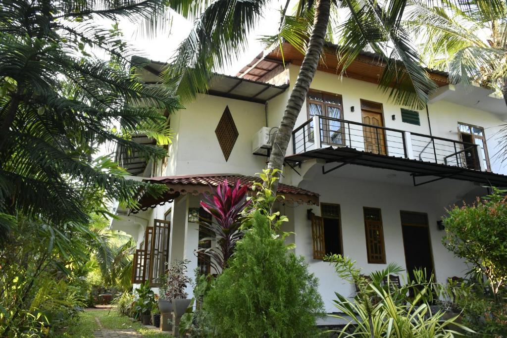 亭可马里Pearl Bungalow Trincomalee的带阳台和棕榈树的白色房屋