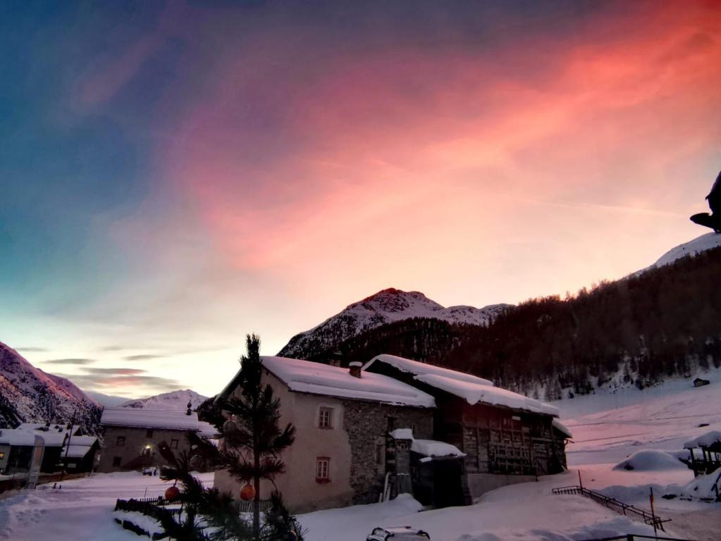 利维尼奥Baita Bruno Fior di Loto的雪中的房子,背景是日落