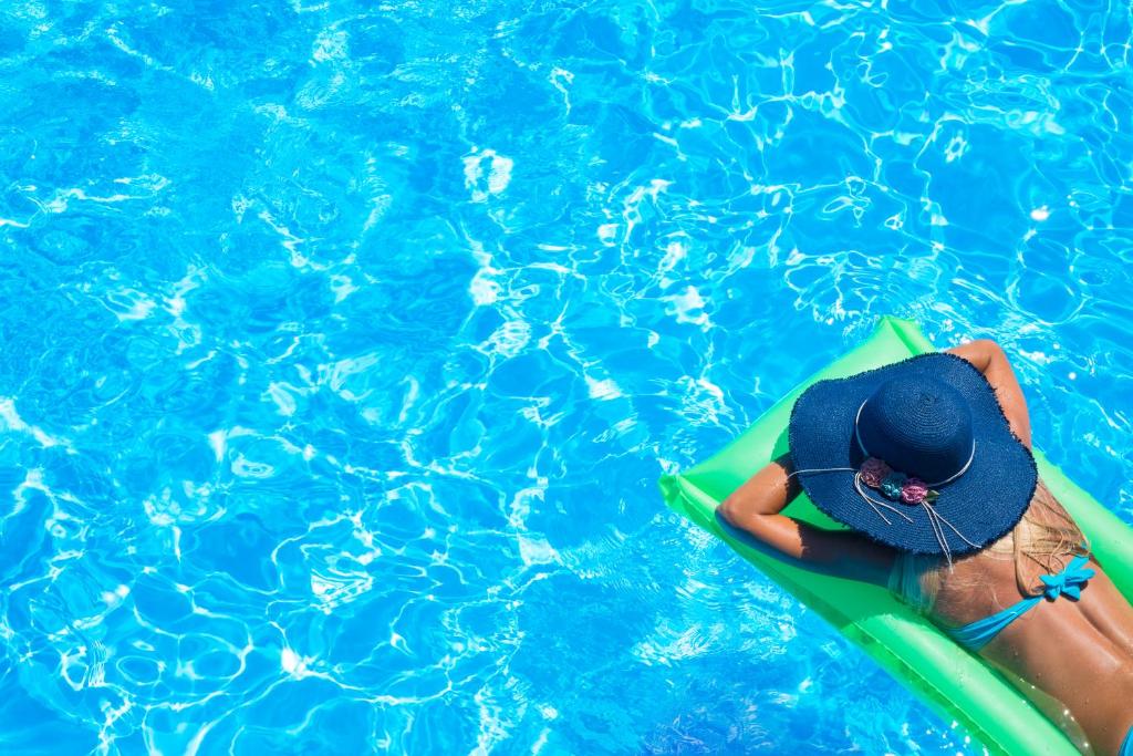 马拉库塔Mallacoota Hotel Motel的游泳池里冲浪板上戴帽子的人