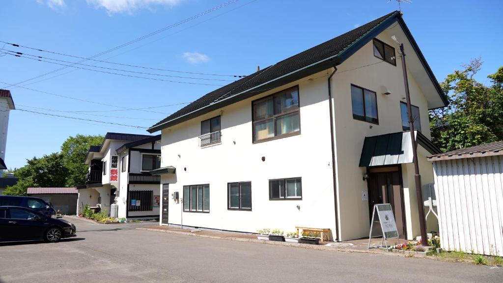 KawayuKawayu Onsen Guesthouse NOMY的前面有一辆汽车停放的白色房子