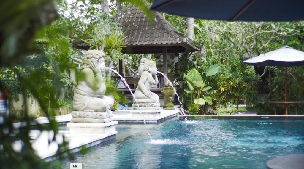 乌布乌布光环度假酒店的花园内带两座雕像的游泳池