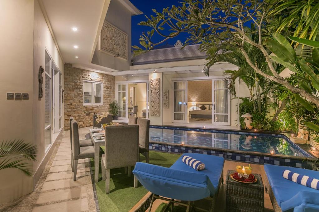 勒吉安Awila Villas Kuta的一个带游泳池和用餐室的户外庭院