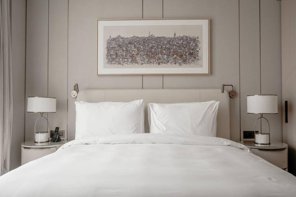 伊斯坦布尔Serviced Luxurious 3+1 in Address Emaar Square的一间卧室配有一张带两盏灯的大型白色床。