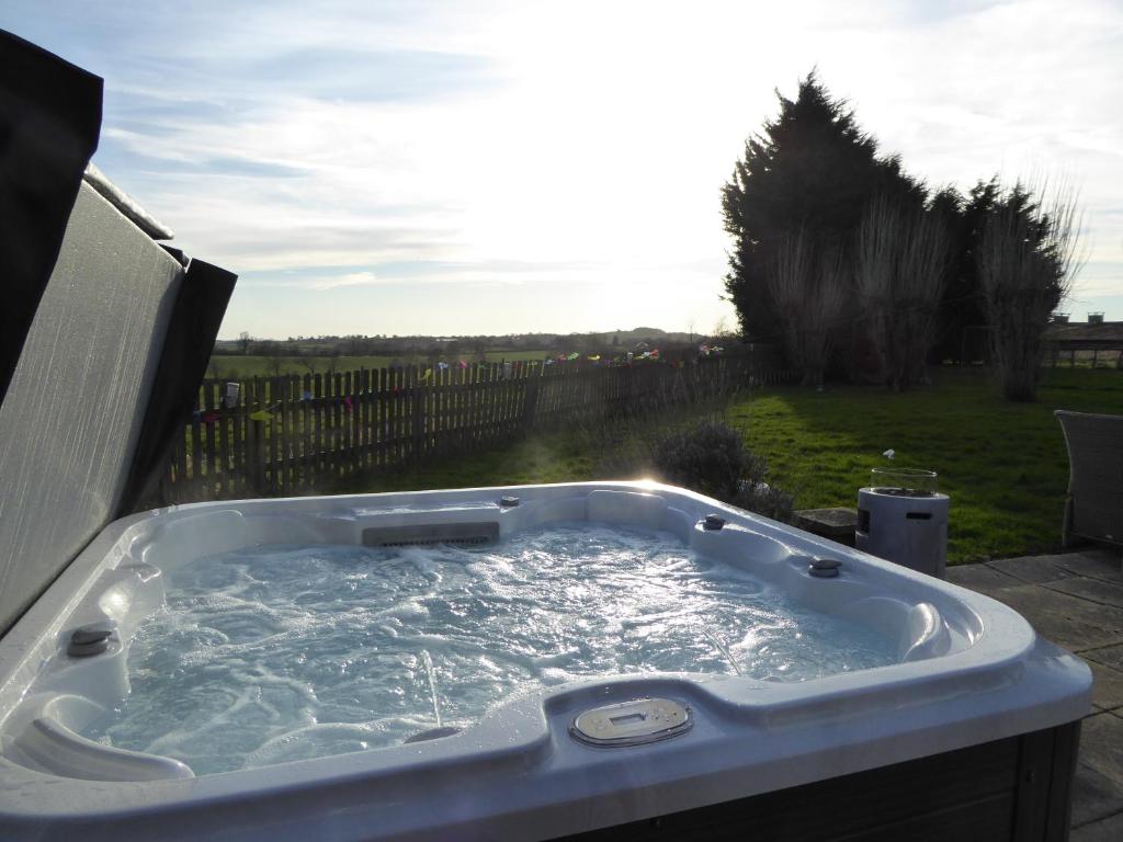 亨利因阿登South View Country House Sleeps 12 - Hot Tub - Views的按摩浴缸位于院子里,阳光明媚