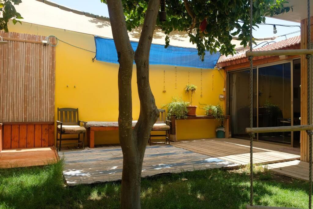 埃拉特Cosy Family Home & Garden in Eilat的一个带椅子的木制甲板和黄色的房子