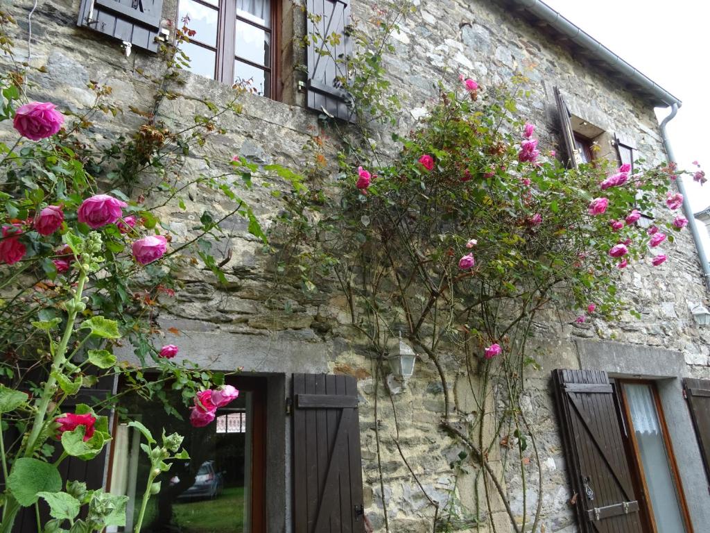 RoudouallecGîte au coeur de la Bretagne的一座石头建筑,上面长着粉红色的玫瑰