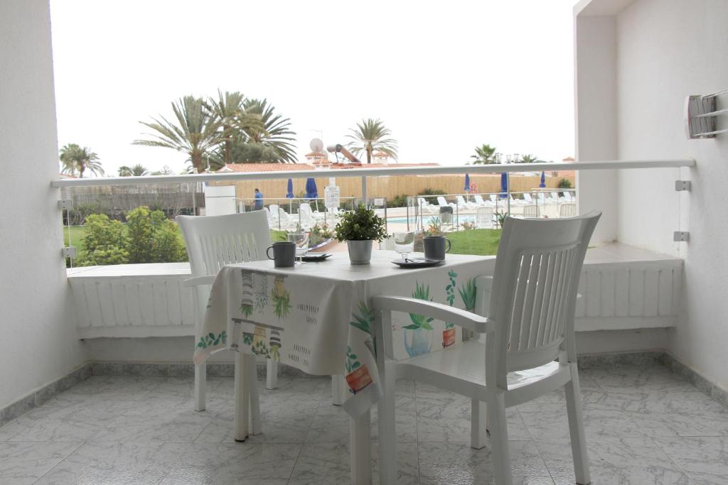 英格兰海滩Estancia en Complejo Tamarán - Playa del Inglés的美景阳台配有白色的桌椅